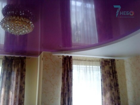 Двухуровневый фиолетовый лаковый и белый матовый потолок с нарядной люстрой