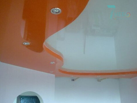 Двухуровневый оранжевый и белый глянцевый потолок с точечными светильниками