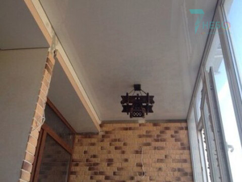 Белый глянцевый потолок с люстрой и декоративной лентой вставкой по периметру