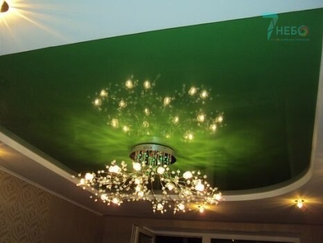 Двухуровневый зеленый глянцевый и белый сатиновый потолок с точечными светильниками и люстрой