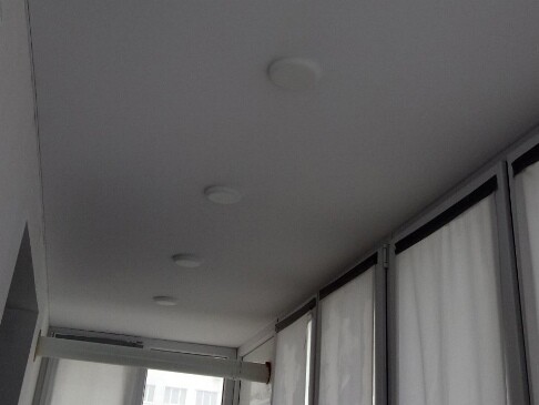 Белый глянцевый потолок с люстрой и декоративной лентой вставкой по периметру