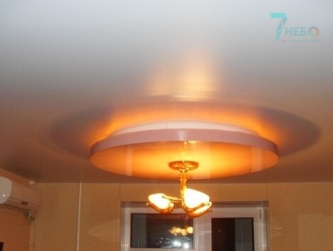 Двухуровневый цветной потолок с подсветкой и светильником в зале частного дома